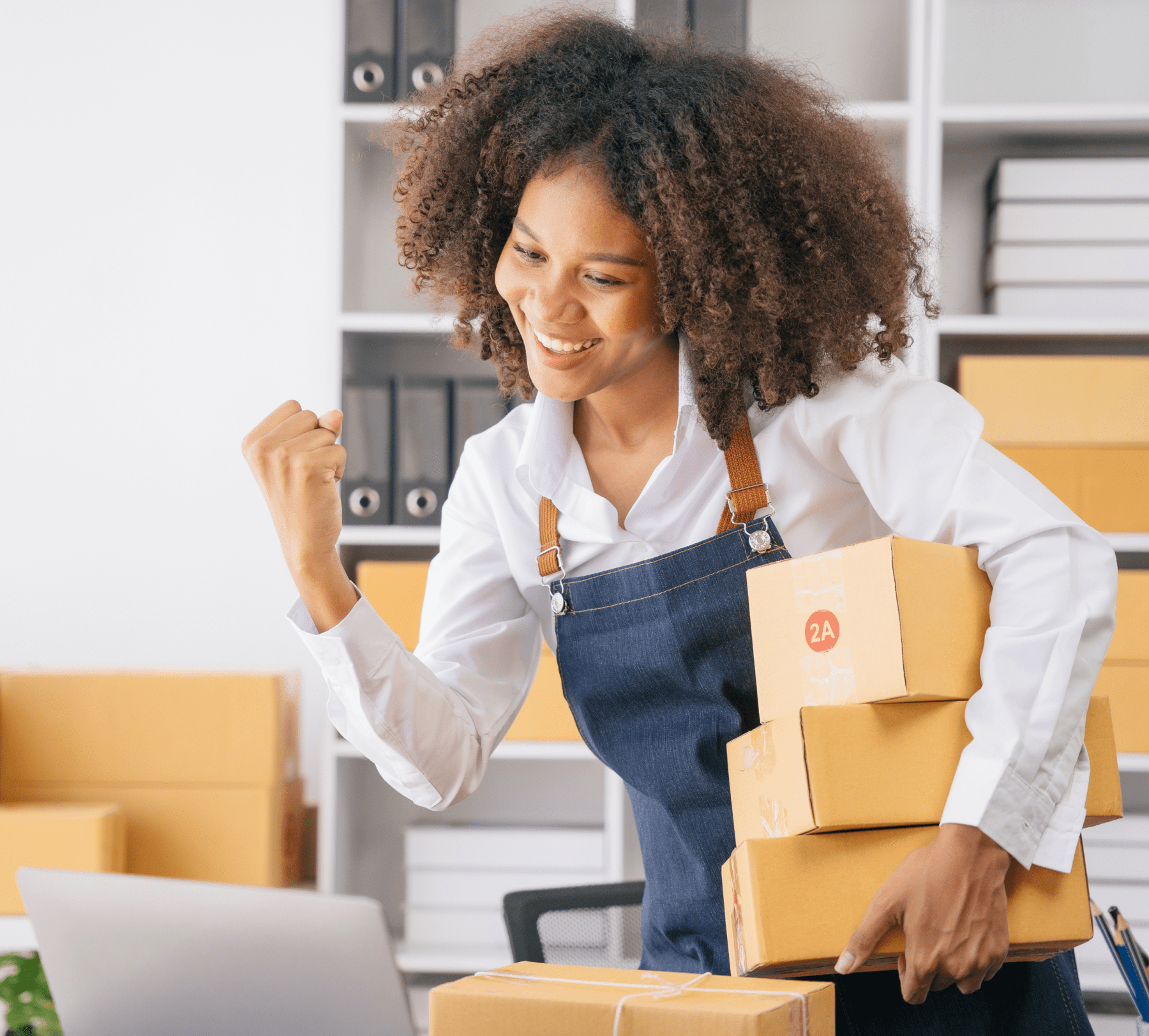A woman happily packing boxes in a workspace.